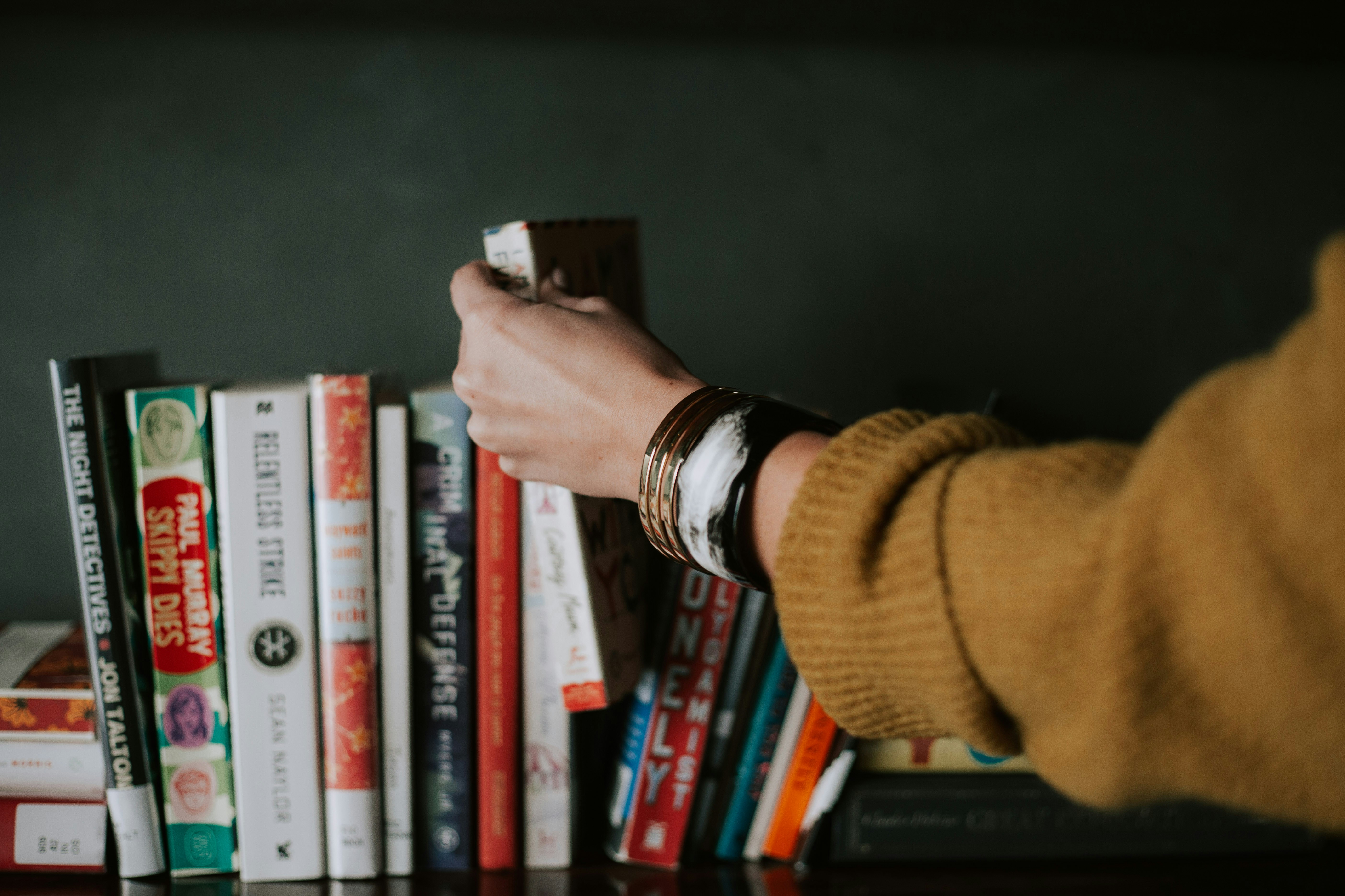 person picking a book from a shelf